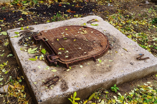 Roestig gietijzeren deksel van een antiek mangat. De foto is genomen in Rusland, in Orenburg