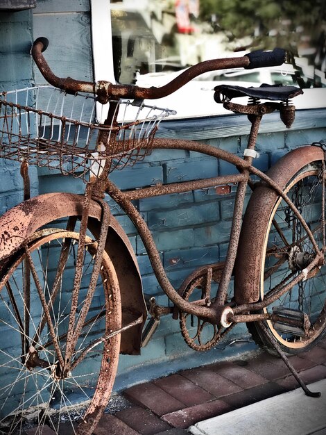 Foto roestige fiets tegen de muur.