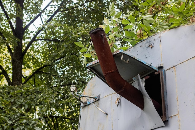 Foto roestige metalen schoorsteen op een achtergrond van groene bladeren op boomtakken