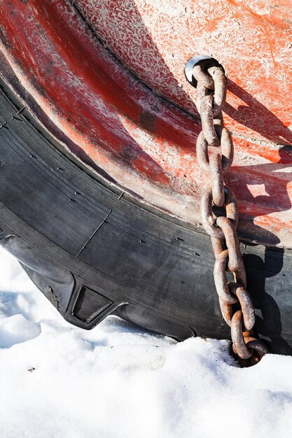 Roestige sneeuwketting gemonteerd op tractorwiel