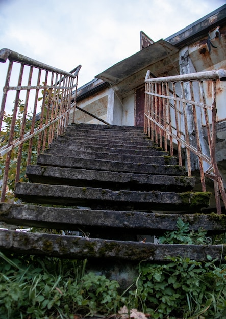 Roestige trap van een verlaten gebouw begroeid met gras en mos