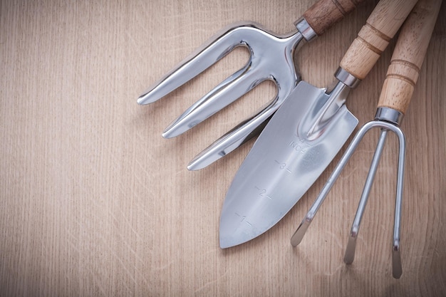 Roestvrij hand spade troffel vork en tuinhark op houten plank landbouw concept