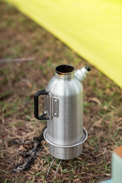 Roestvrijstalen waterkoker wordt op het fornuis geplaatst om water te koken voor koken en koffie. Ochtend, kamperen