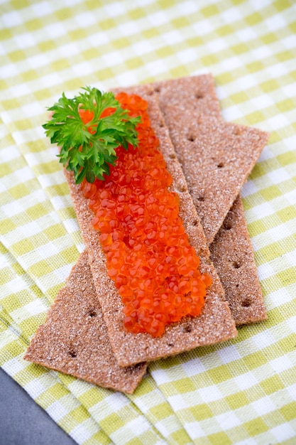 Rogge knäckebröd met zachte kaas met kruiden en zalmeitjes.