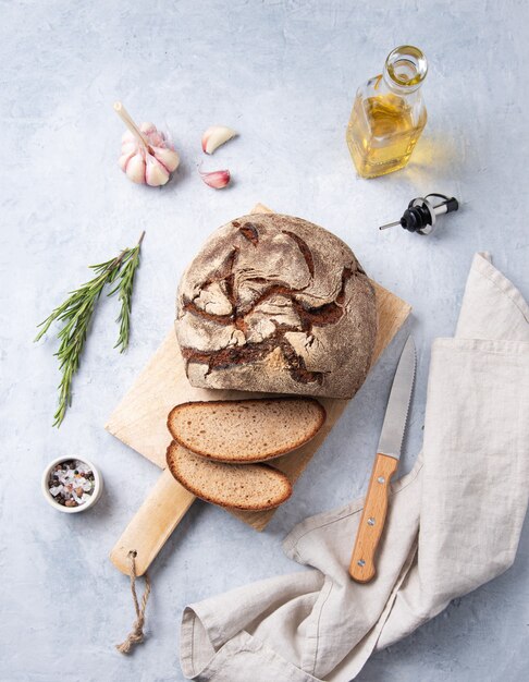 Roggebrood gesneden op een houten bord met rozemarijn, knoflook en olijfolie