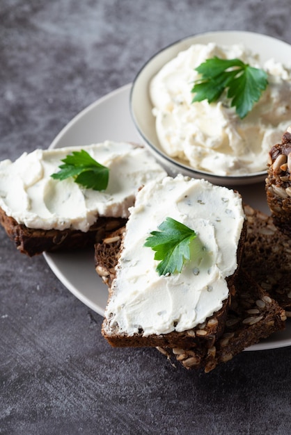 Roggebrood met roomkaas op grijze tafel Volkoren roggebrood met zaden