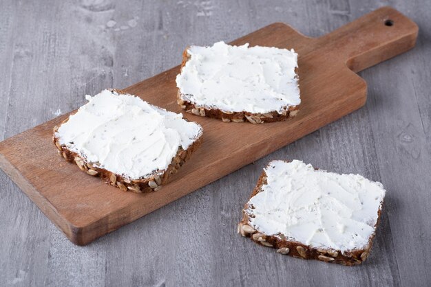 Roggebrood met roomkaas op grijze tafel