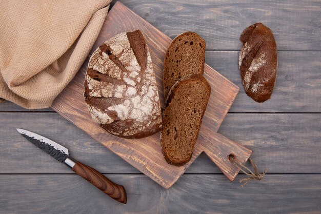 Roggebrood rond brood in stukjes gesneden op een houten bord met een mes gemaakt van rustiek hout. Bovenaanzicht.