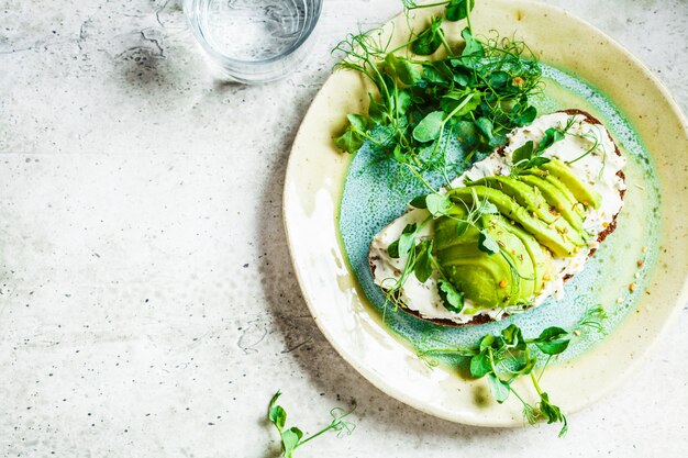 Roggebroodtoost met roomkaas en avocado op mooie plaat, hoogste mening