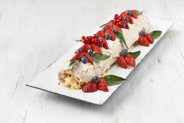rol meringue pavlova cake met room en frambozen, bramen en bosbessen erop