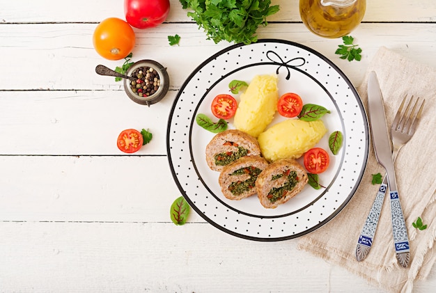 Rol van kalkoengehakt met spinazie en rode paprika met garnituur van aardappelpuree