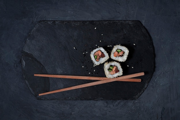 Rol zalm teriyaki, op een zwarte steen staat, bovenaanzicht, geen mensen, horizontaal. Hoge kwaliteit foto