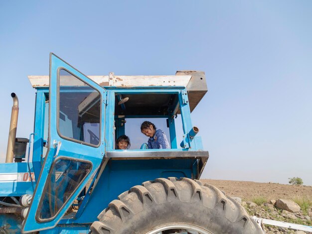 Roleplaying children imagining themselves as farmers while playing on a tractor in the field