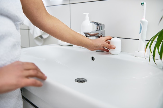 A roll-on antiperspirant on the bathroom washsbasin.