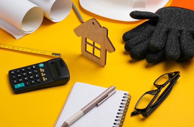 Roll drawings, engineering tools and stationery on yellow background, House building concept