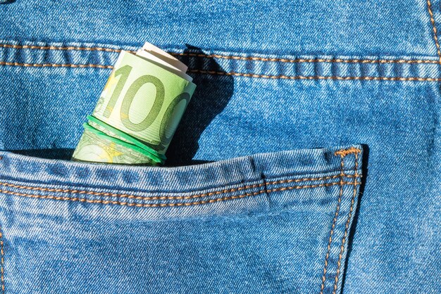 Roll of euro banknotes in a blue jeans pocket