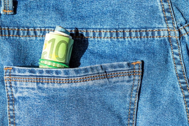 Roll of euro banknotes in a blue jeans pocket