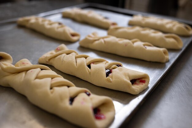 A roll filled with currant and raspberry jam lies on a metal\
board preparation for baking homemade cakes in the kitchen