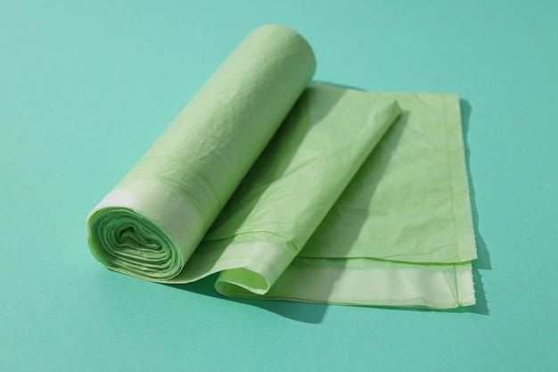 Roll of garbage bags on green background close up