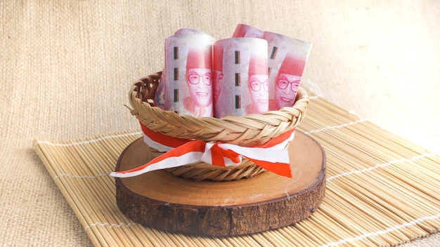 Roll of one hundred Indonesia Money Rupiah on wicker basket tied with red white ribbon Selective Focus