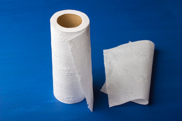 Photo roll of paper towel on a blue, wooden background.