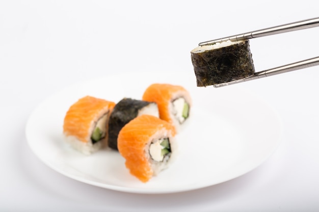 Roll of sushi on a plate, Sushi roll on a tablet, white background, Sushi roll and hand with chopsticks