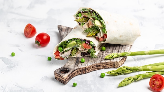 roll tortilla met gegrilde kipfilet met asperges, avocado, tomaten, doperwten, kaas en tartaar