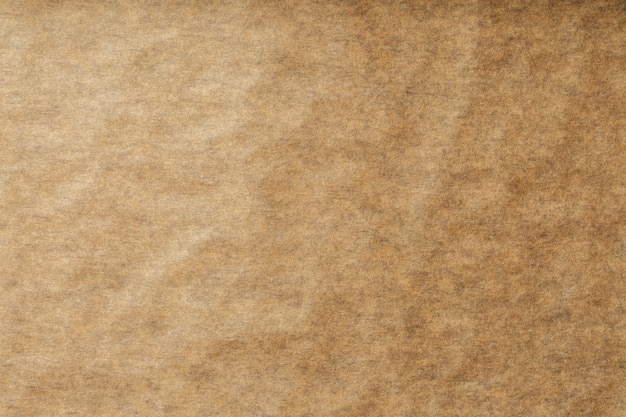 Photo a roll of unfolded brown parchment paper, for baking food in background, top view.