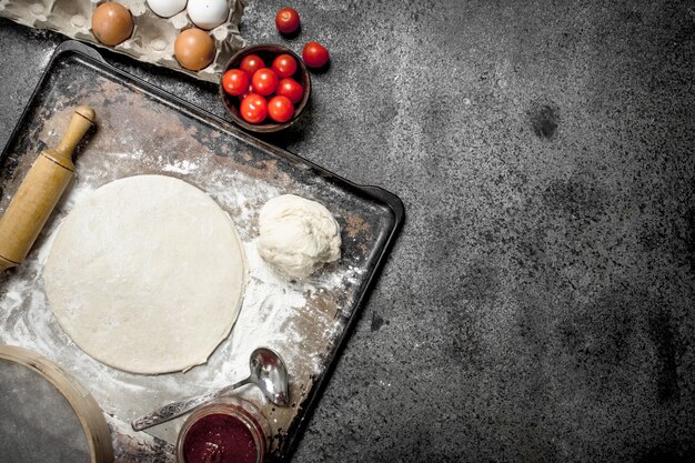 Roll up dough with ingredients for pizza. On a rustic background.