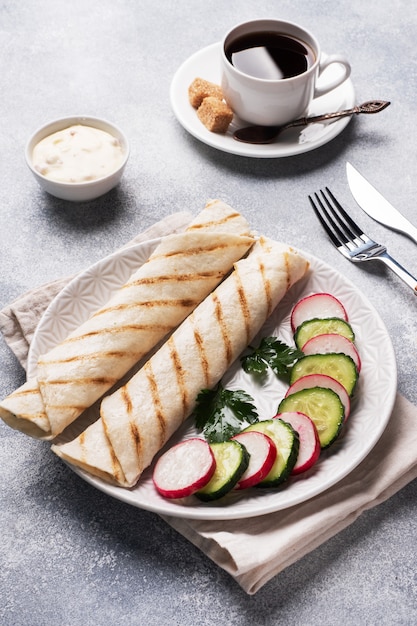 Roll with cheese and herbs. Grilled pita bread with filling. Cucumber radish salad. The concept of a healthy Breakfast. Cup of coffee.