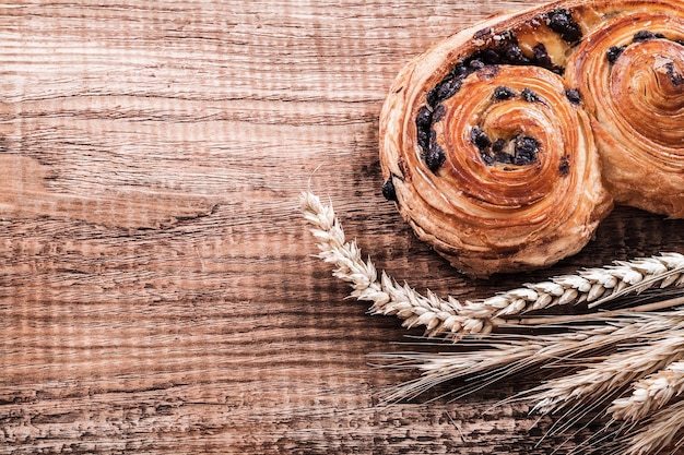 Rotolo con spighe di grano uvetta su tavola di legno di quercia concetto di cibo e bevande