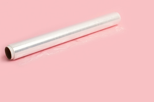 A roll of wrapping plastic stretch film on a pink background