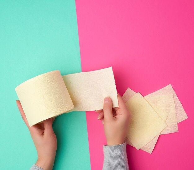 Roll of yellow toilet paper in female hands