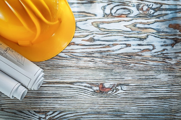 Rolled construction plans building helmet on vintage wooden board