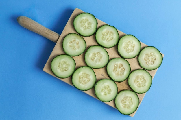 Photo rolled cucumber on a kitchen board placed all on a blue background preparing the summer