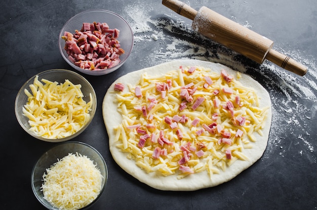 Impasto arrotolato, farina da forno, ripieno per pizza e mattarello