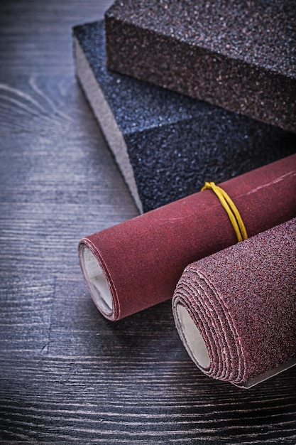 Rolled emery paper sanding sponges on vintage wooden board abrasive materials.