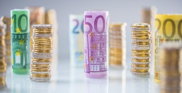 Свернутые банкноты евро и башни монет сложены в других положениях.