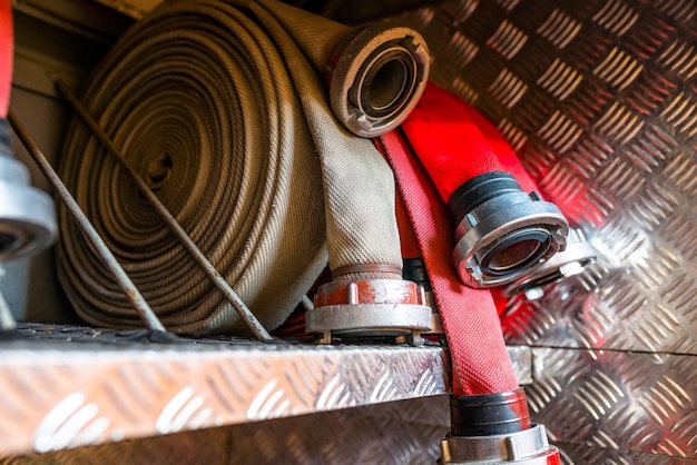 Rolled fire hoses arranged in rows in the glove compartment of the fire truck