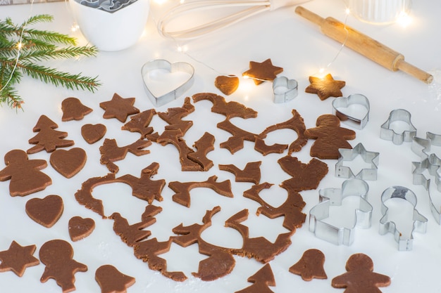 rolled ginger dough, cut pieces of dough for cookies, baking tins, rolling pin, spruce branches, garland