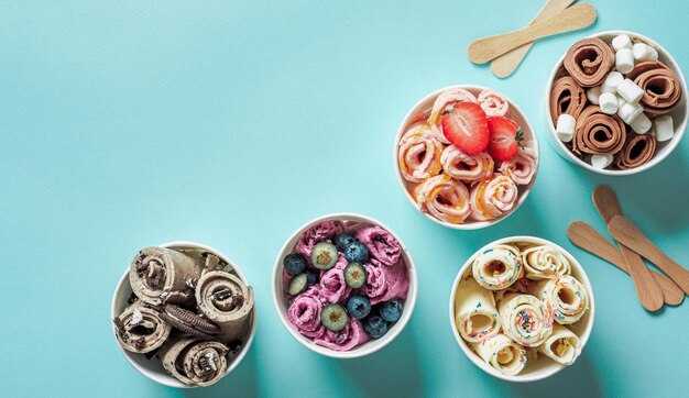 Photo rolled ice creams in cone cups on blue background different iced rolls top view or flat lay thai style rolled ice cream with copy space for text or design banner