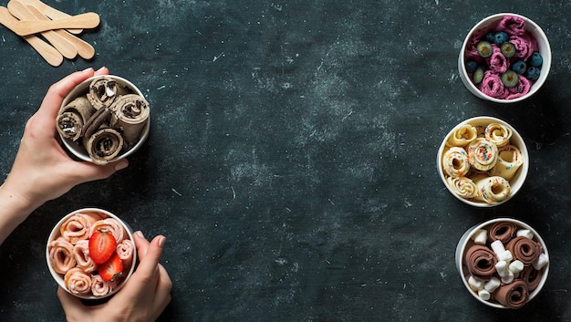 rolled ice creams in cone cups on dark background