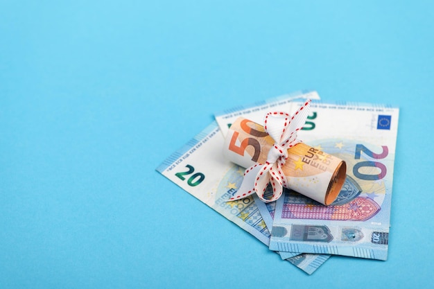 Photo rolled into a roll of 50 euros on a light blue background of 20 euro banknotes