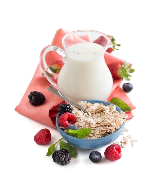 Rolled oats in a bowl with berries and milk isolated on white