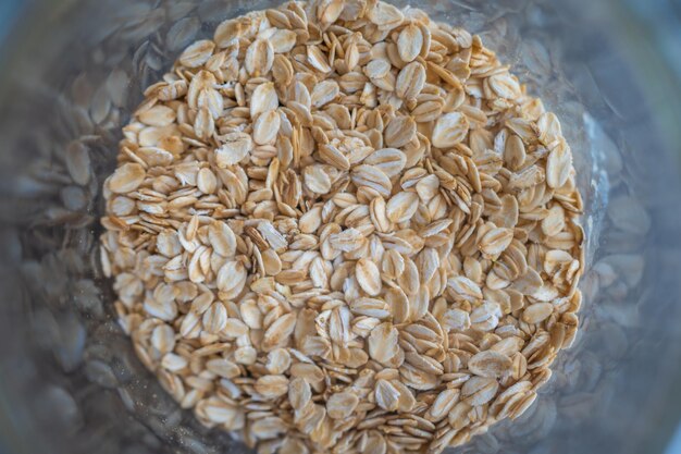 Rolled oats in a glass bowl top view on a grey background