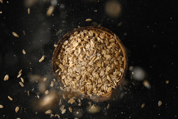 Rolled oats grain in a coconut bowl on a dark gray surface