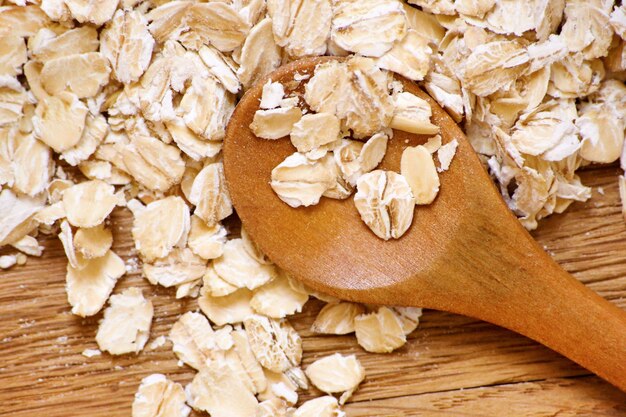 Rolled oats and oat ears of grain on a wooden table, close-up