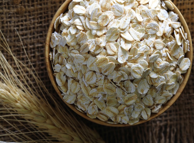 Rolled oats  in a wooden bowl on a sack