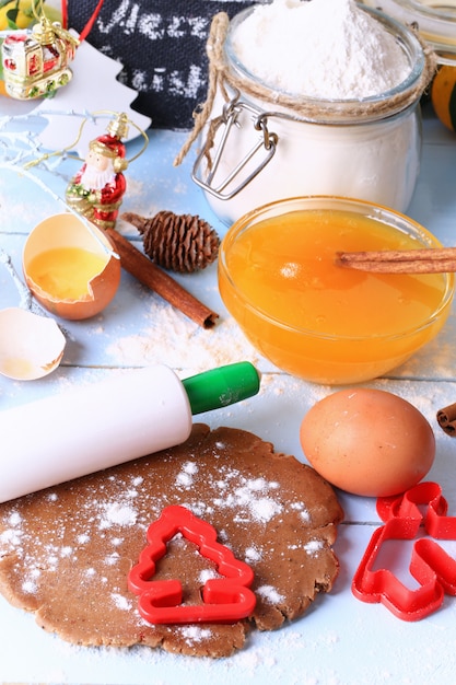 Rolled out dough for gingerbread Christmas homemade cakes on a light wooden background selective soft focus rustic style