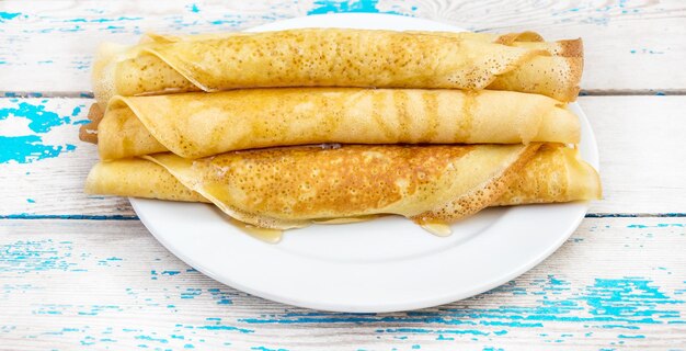Rolled pancakes with honey on the old wooden background